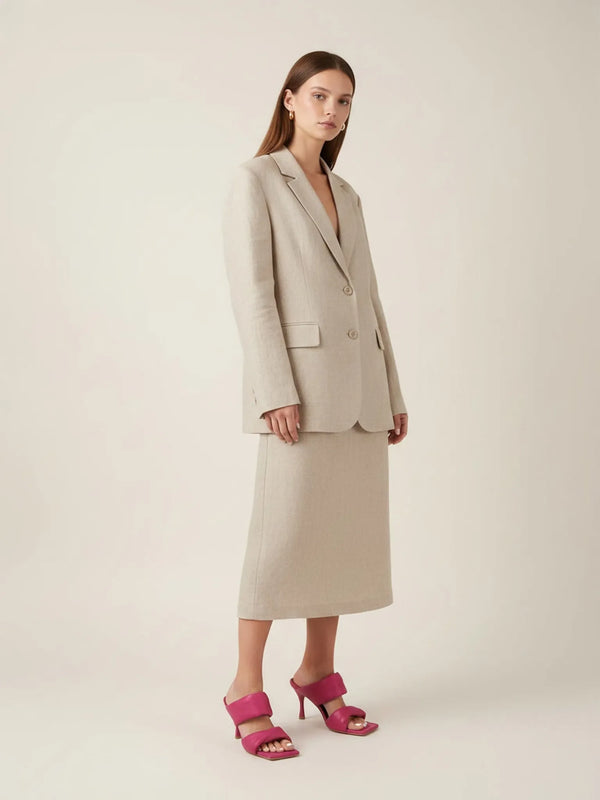 Woman wearing a beige suit with pink sandals on a white background