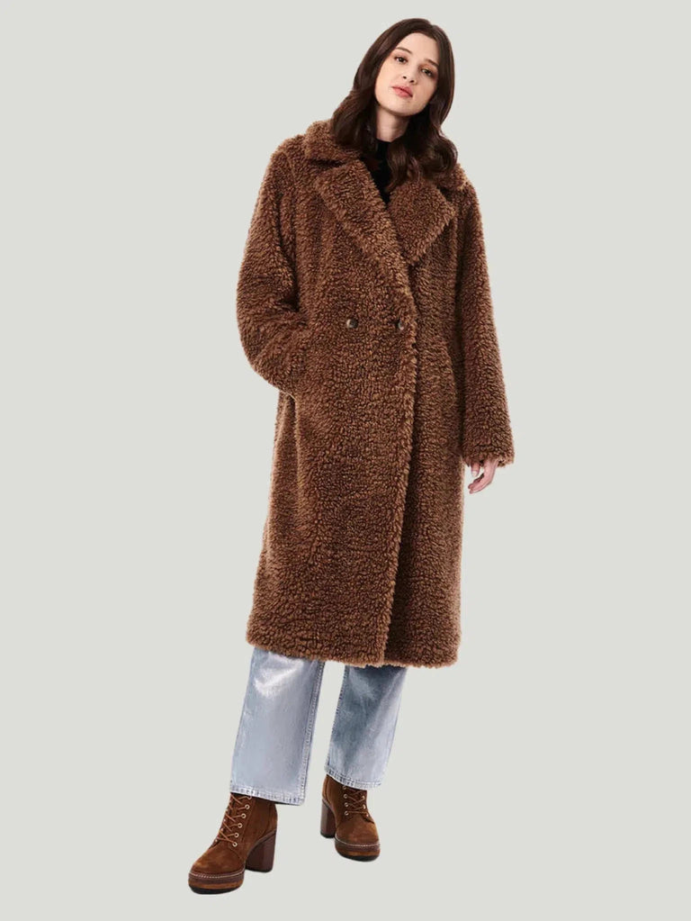 Teddy Embrace Vegan Fur Coat by Bernardo, oversized and below knee-length, in luxurious teddy texture. Made with 100% polyester faux fur and lined with 100% recycled polyester, it features eco-friendly Ecoplume™ insulation for extra warmth. Model is 5’10” and wears size S. Dry clean only. This coat combines style with sustainability, using insulation from 100% post-consumer recycled plastic bottles."