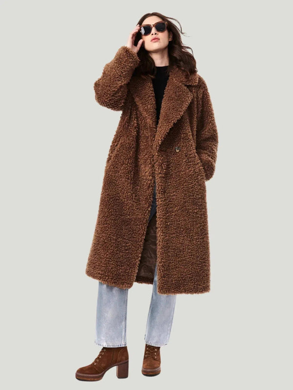 Teddy Embrace Vegan Fur Coat by Bernardo, oversized and below knee-length, in luxurious teddy texture. Made with 100% polyester faux fur and lined with 100% recycled polyester, it features eco-friendly Ecoplume™ insulation for extra warmth. Model is 5’10” and wears size S. Dry clean only. This coat combines style with sustainability, using insulation from 100% post-consumer recycled plastic bottles.