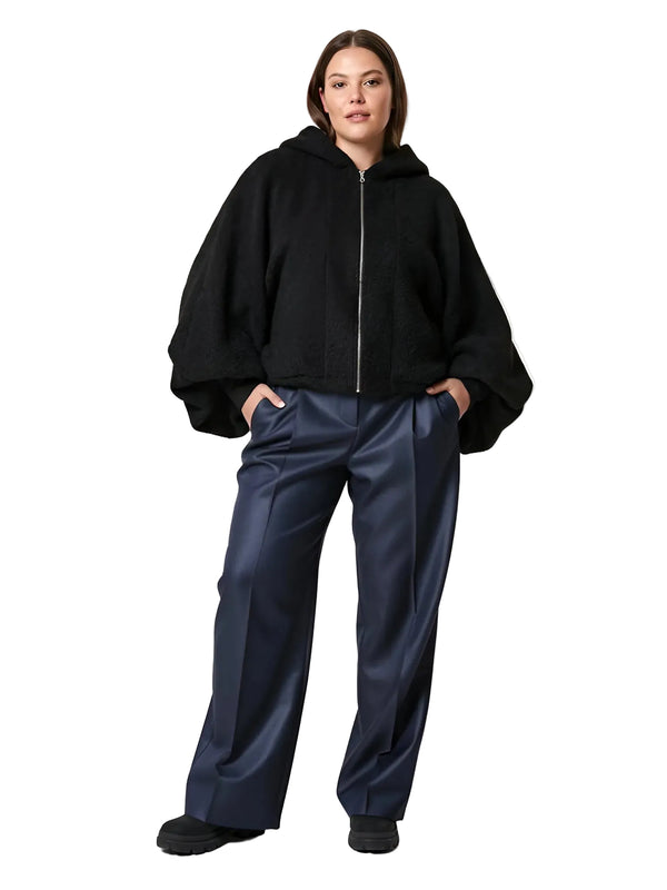 Person wearing a black hoodie and navy pants on a white background