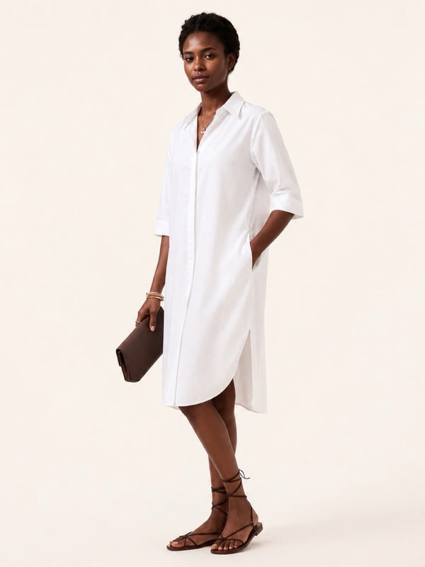 Woman wearing a white shirt dress on a plain background
