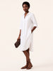Woman wearing a white shirt dress on a plain background