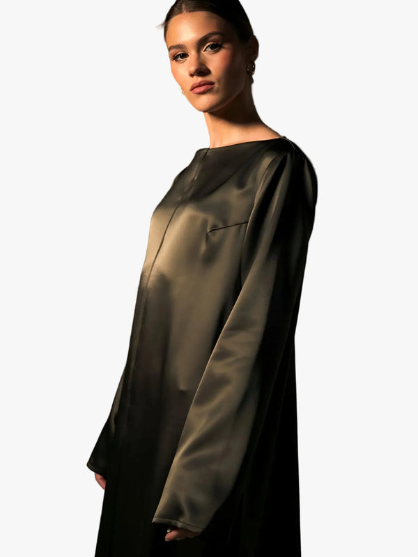 Woman wearing a dark green satin dress against a brown background