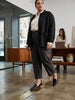 Journee Collection Maggs black leather pointed-toe flat loafers with a wooden heel, worn by a woman in an office setting.