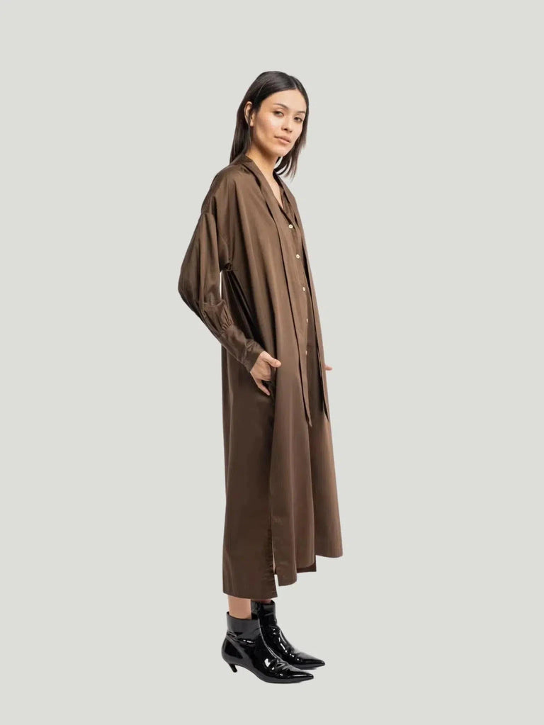 "The Dolores Poplin Midi Dress in basalt brown exudes sophisticated charm, featuring an extended collar, full sleeves, and bold cuffs, crafted from 100% organic cotton poplin, reflecting Queen Anna House of Fashion's commitment to ethical and eco-conscious style.