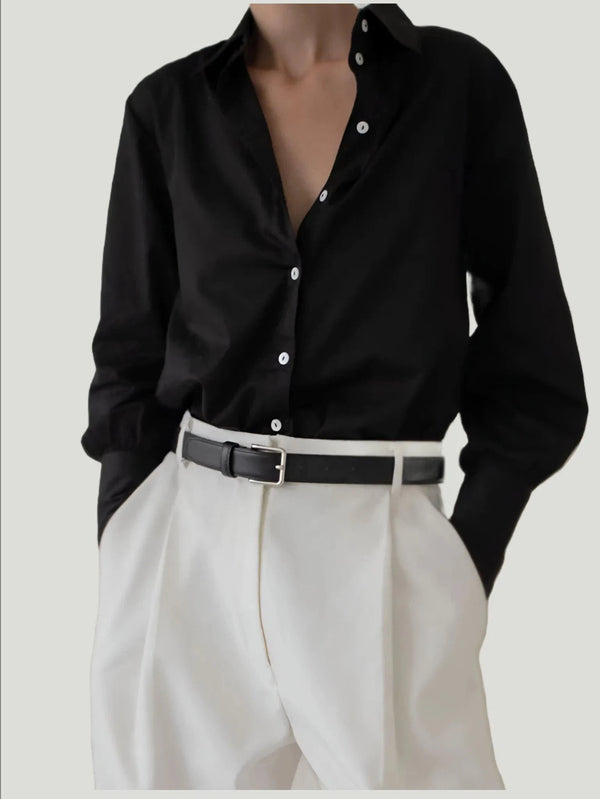 Black Museo Button-Up by LAUDE The Label: Delicately elegant design meets modern touches, with statement cuffs on long, flowing sleeves. Made of 100% Organic Cotton, this oversized shirt boasts mother-of-pearl buttons, symbolizing sophisticated style. Eco-conscious and crafted by a women-owned brand
