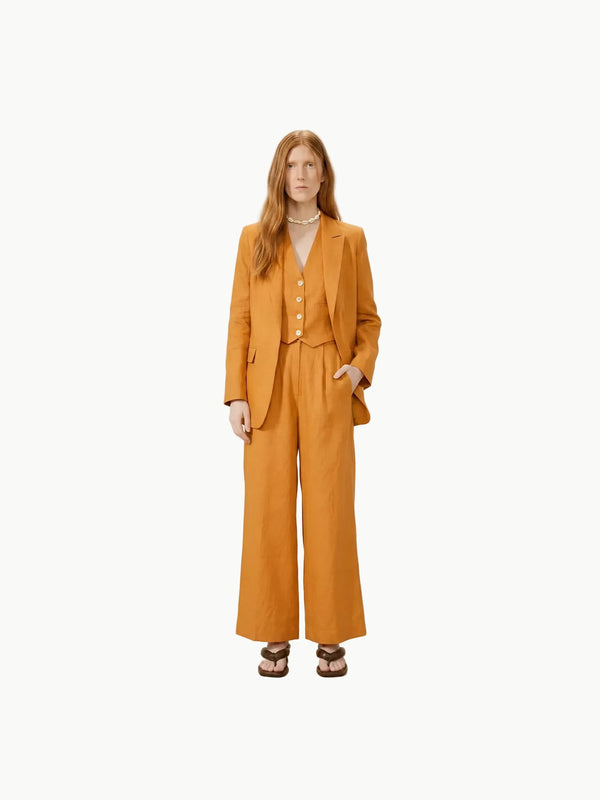 Woman wearing a mustard yellow suit against a white background