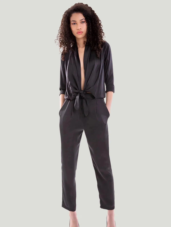 Model showcasing a chic and sophisticated Betty jumpsuit with draped neckline, front tie closure, and elasticized waistband. Crafted in luxurious Satin Georgette, 100% Viscose. Ideal for versatile styling, day to night.