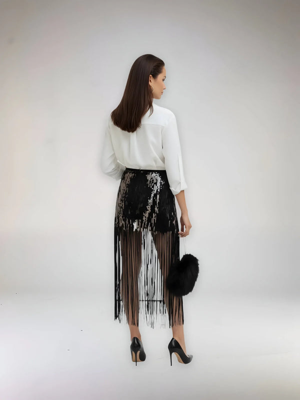 Woman wearing a white blouse and black fringe skirt with a white background