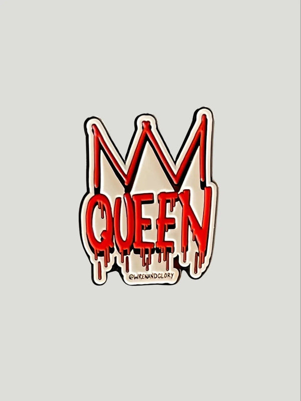The 'Queen' enamel pin by Wren and Glory, a tribute to regal elegance. This 1.5-inch pin features a striking queen and crown graphic in vibrant colors, set against a high-quality, soft enamel surface. The metal backing ensures durability, and the pin is uniquely signed by @wrenandglory. Perfect for adding a touch of sophistication to any outfit, this pin embodies the empowerment and style celebrated at Queen Anna House of Fashion.