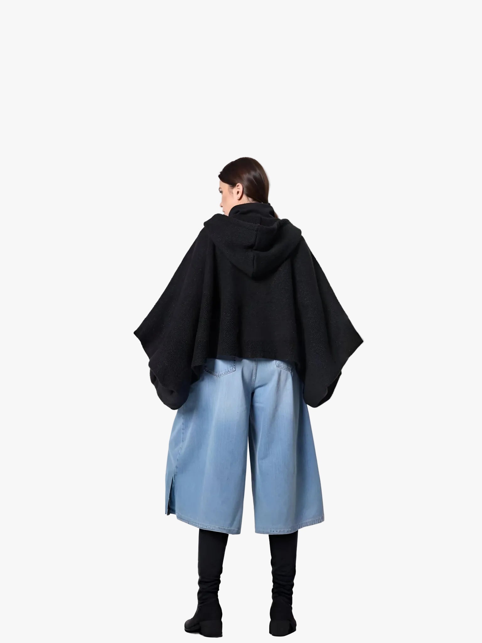 Person wearing a black hooded coat and light blue pants standing against a white background