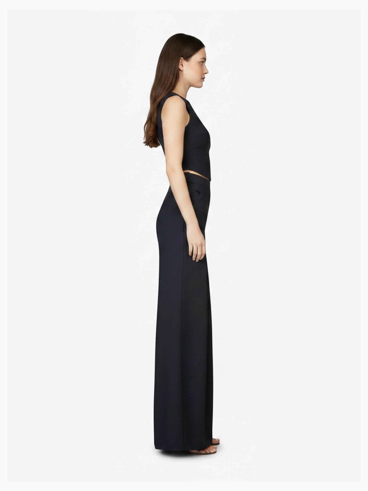Side profile of model wearing Article X Black Wide Leg Pant and sleeveless crop top, showing structured design