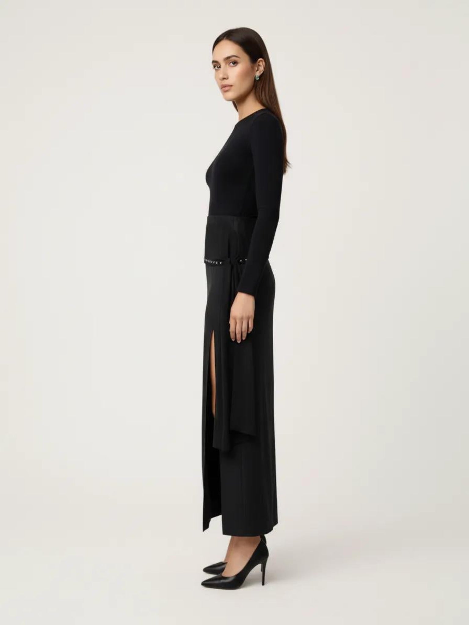 Woman wearing a black dress with a slit on a white background