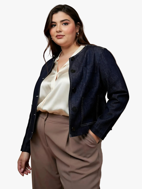 Woman wearing a dark denim jacket over a cream blouse and beige pants on a brown background