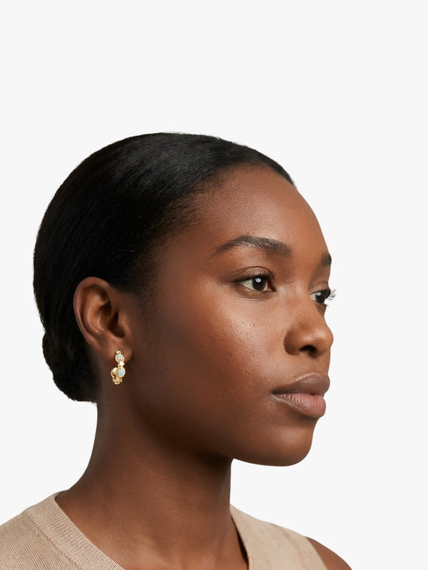 Woman wearing gold earrings on a plain background