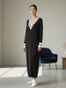 Lifestyle view of the Lanhtropy Preppy Knitted Dress in black, worn by a model sitting in a blue armchair in a modern indoor studio setting.