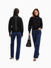 Queen Anna House of Fashion black knit sweater featuring white contrast stitching on shoulders and back, worn with jeans.