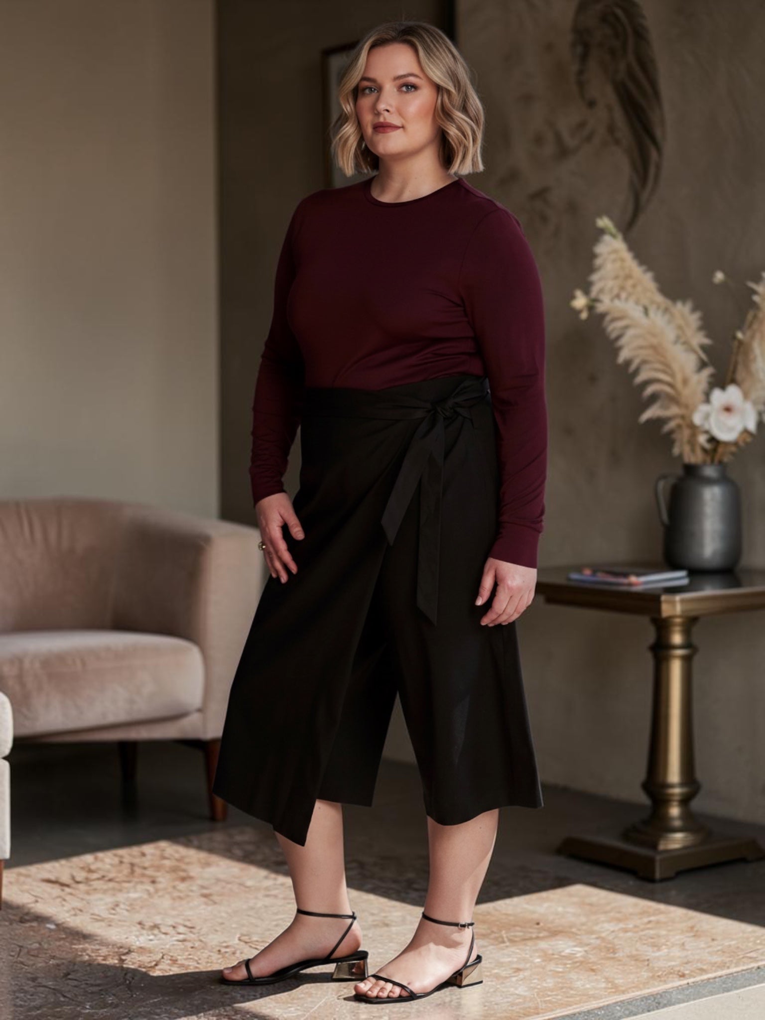 Queen Anna House of Fashion model wearing black Universal Standard linen wrap culottes with a burgundy long-sleeve top