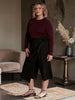 Queen Anna House of Fashion model wearing black Universal Standard linen wrap culottes with a burgundy long-sleeve top
