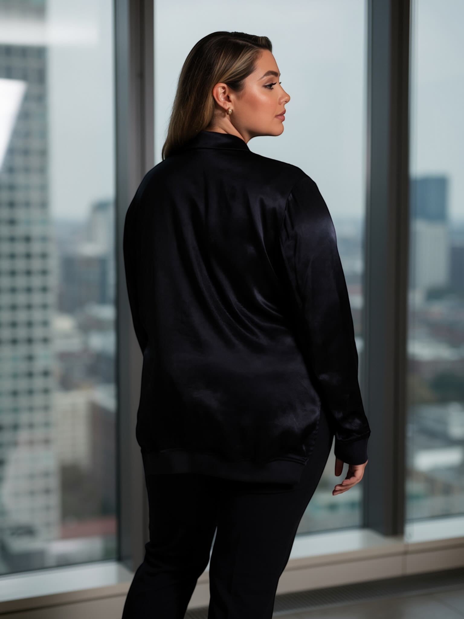 Queen Anna House of Fashion model wearing a black Universal Standard satin bomber jacket with a relaxed fit