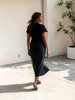 Model wearing a black Queen Anna House of Fashion Divine Jersey shift dress with short sleeves and a midi length.