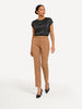 Model wearing a Queen Anna House of Fashion black washable silk charmeuse top tucked into tan tailored trousers.