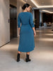Queen Anna House of Fashion blue jersey cinched dress with three-quarter sleeves worn by a woman in a modern hallway.