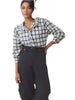 Model wearing a Queen Anna House of Fashion white and black plaid stretch poplin button-front shirt with dark trousers