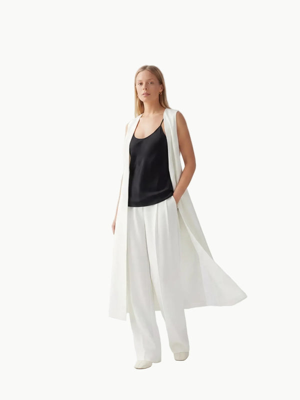 Woman wearing a black top and white long dress against a white background