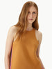 Woman wearing a mustard yellow sleeveless top against a plain background
